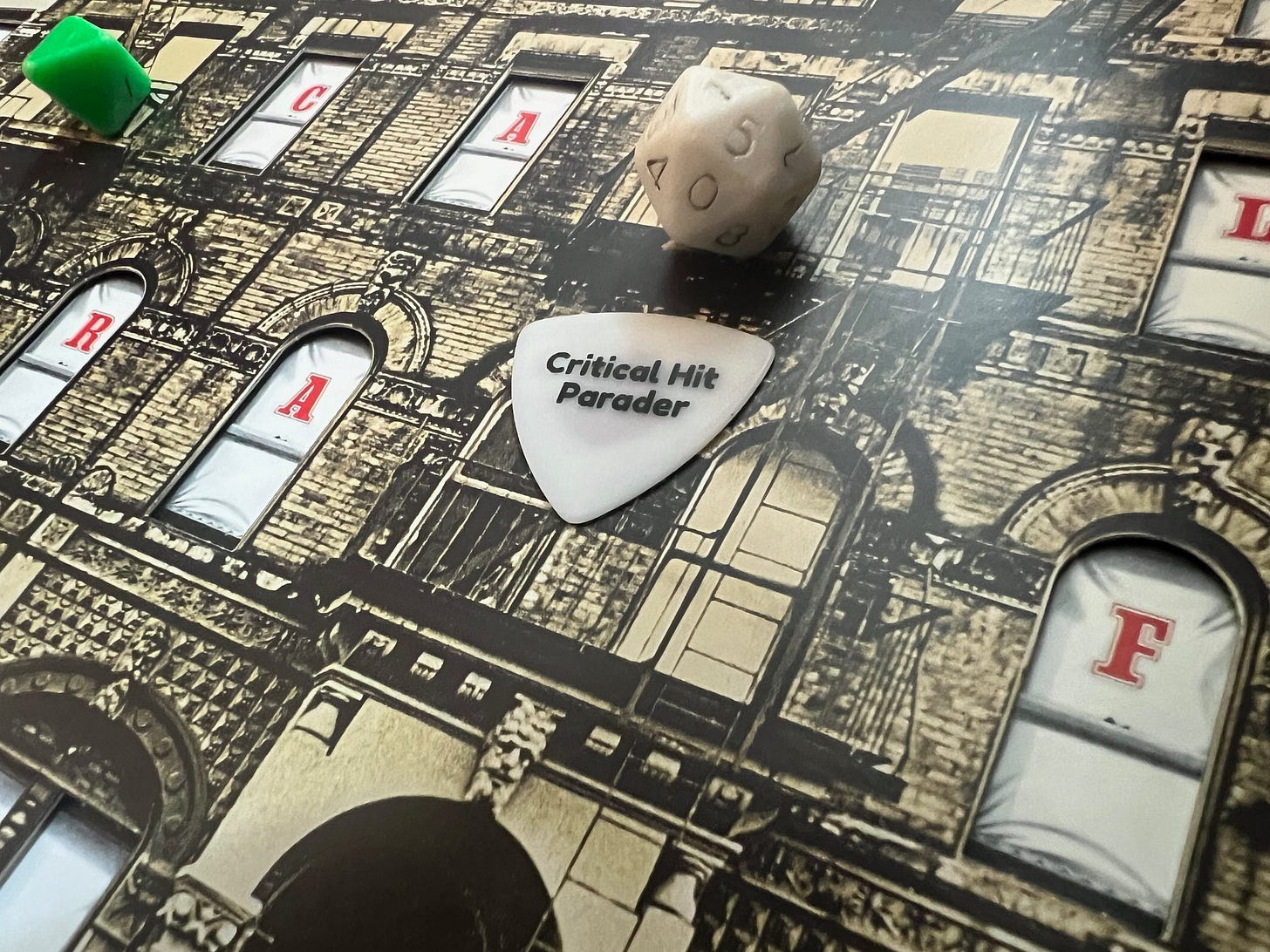 A close up of the Physical Graffiti album by Led Zeppelin with two Holmes box set dice placed on balcony windows. One is a green 8 sider and the other is white 20 sider. Both are worn from decades of clutch rolling. Also on the album cover is an unassuming white Critical Hit Parader guitar pick