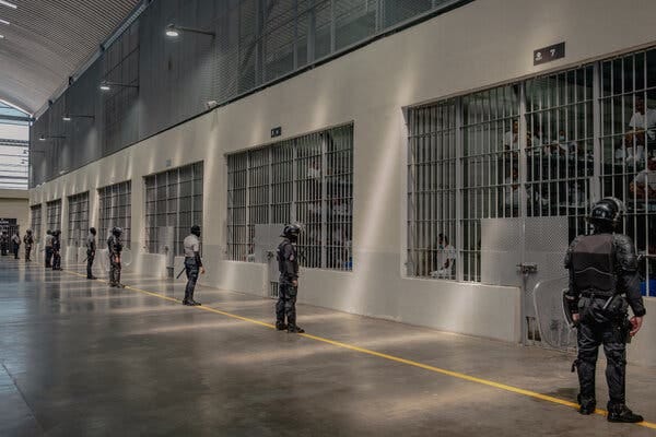 Guardias, con cascos y equipo, frente a varias celdas en una instalación penitenciaria Guardias, con cascos y equipo, frente a varias celdas en una instalación penitenciaria