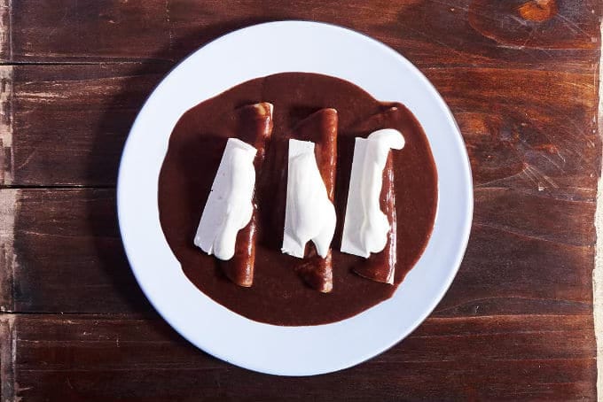 Plate of enchiladas with bean sauce.