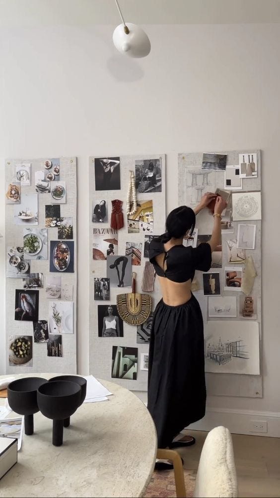 This may contain: a woman standing in front of a white wall with pictures on the wall behind her