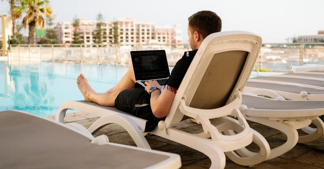 man on sun lounger using laptop