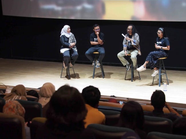 Deux hommes et deux femmes, l'équipe du film, assis sur une scène de cinéma, sous l'écran Deux hommes et deux femmes, l'équipe du film, assis sur une scène de cinéma, sous l'écran