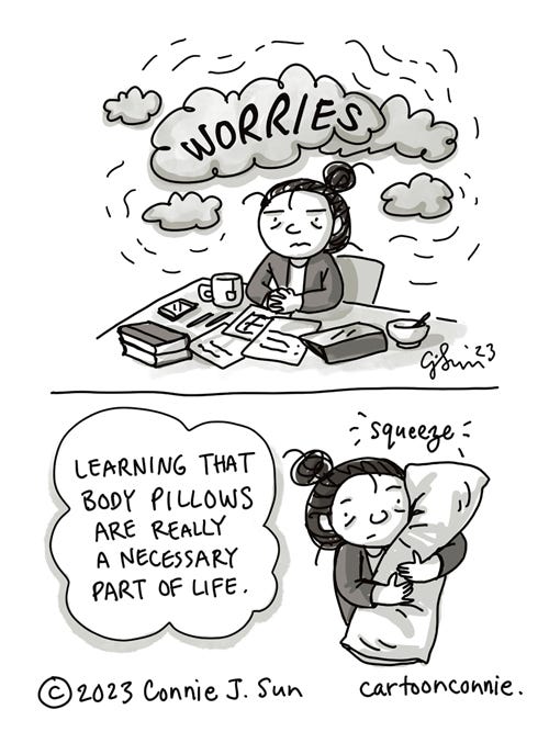 Instant Hugs 2-panel monochrome comic illustration of a girl with a bun, sitting at a cluttered desk, under clouds of worry. In panel 1, she looks burdened and heavy clouds loom over her head, enclosing the word "WORRIES" in bold handwritten text. Panel 2 shows her in a medium shot, hugging a large pillow for comfort. In a lighter bubble, the text reads, "Learning that body pillows are really a necessary part of life," as she gives the pillow a light "squeeze." Comic titled "Instant Hugs." Original artwork by Connie Sun, cartoonconnie, 2023.