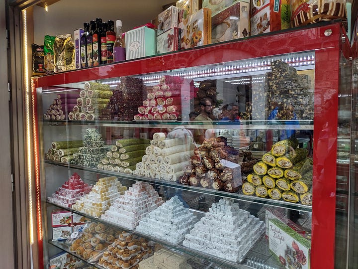 The photo gallery shows four pictures in a square. The top left picture is of a pita with a sour cream sauce and sausage meet. The top right image is of a sweets shop with Turkish and Bosnian sweets. The bottom left is of a wedge slice of green colored cheese and the bottom right is of a red colored wedge shaped slice of cheese.