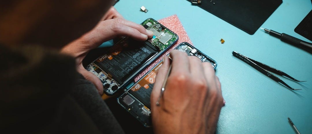 person repairing smartphones under a lighted table