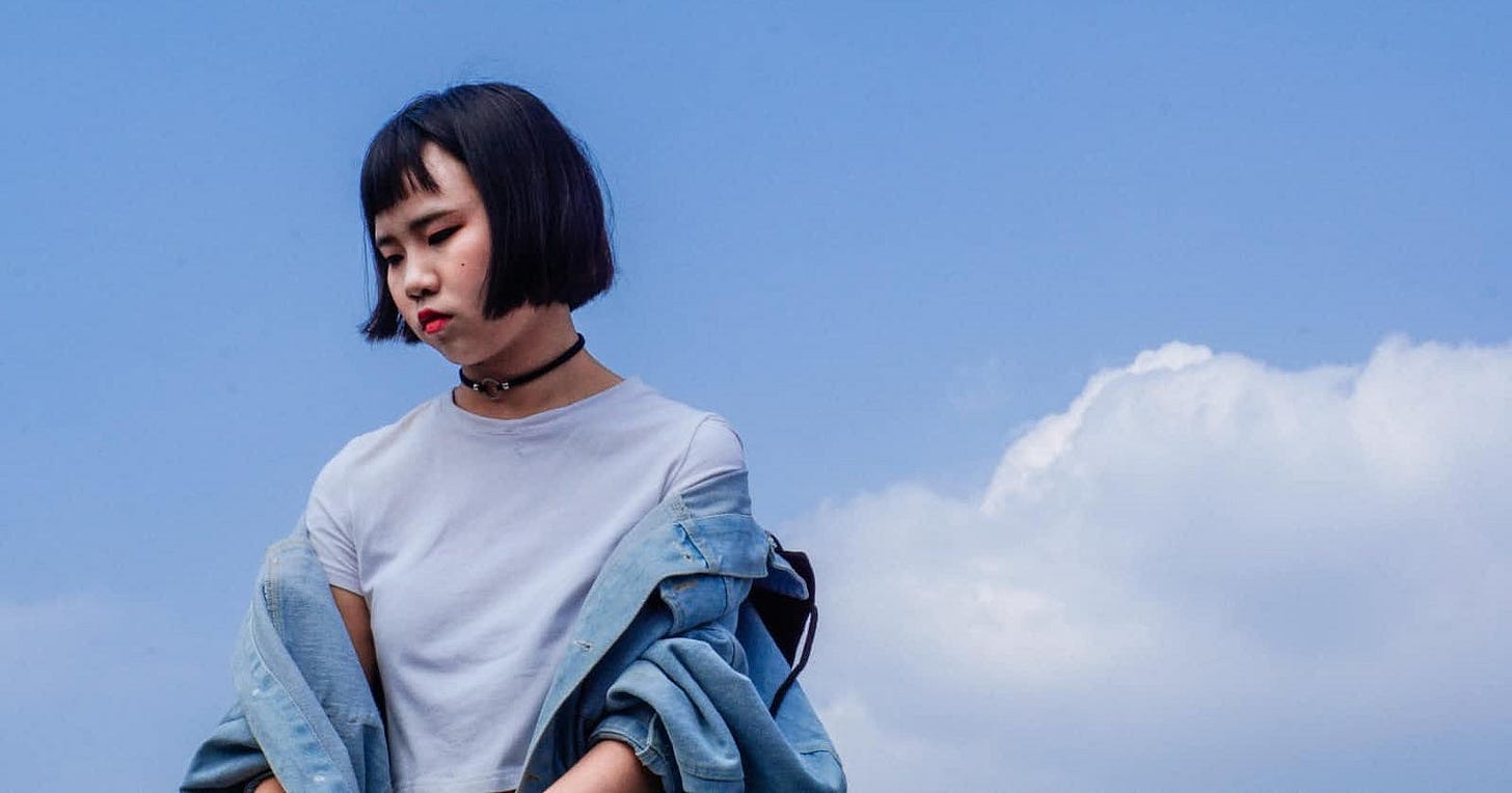 Disappointed woman standing outdoors against a bright blue sky, reflecting the themes of admiration and disillusionment in the 'Twice as Nice' poem.