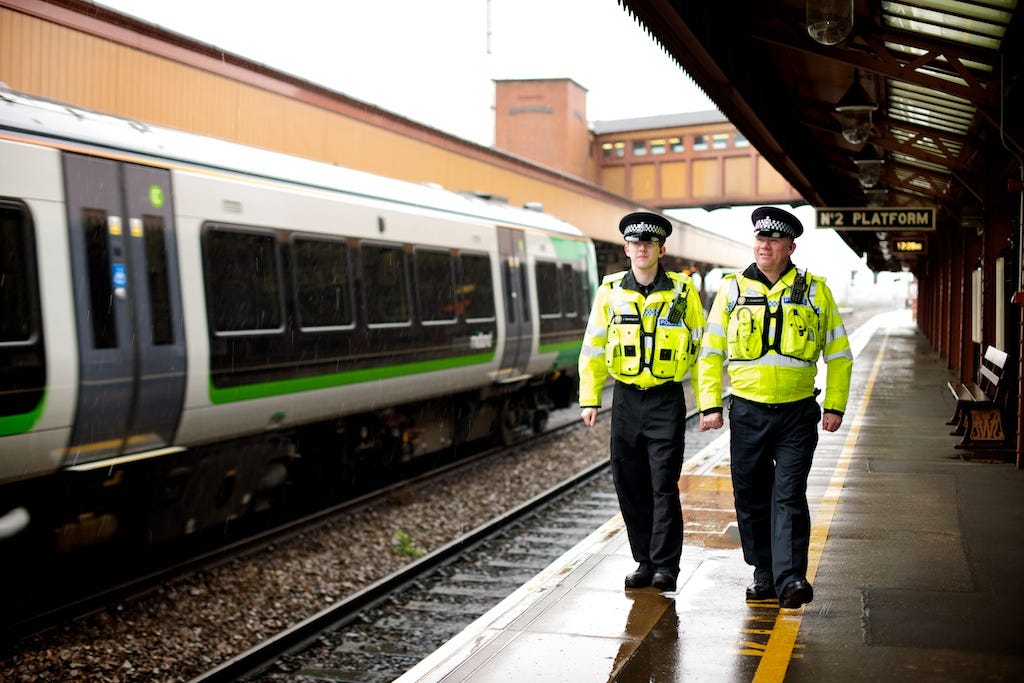 Two police officers patrol a UK railway station Two police officers patrol a UK railway station