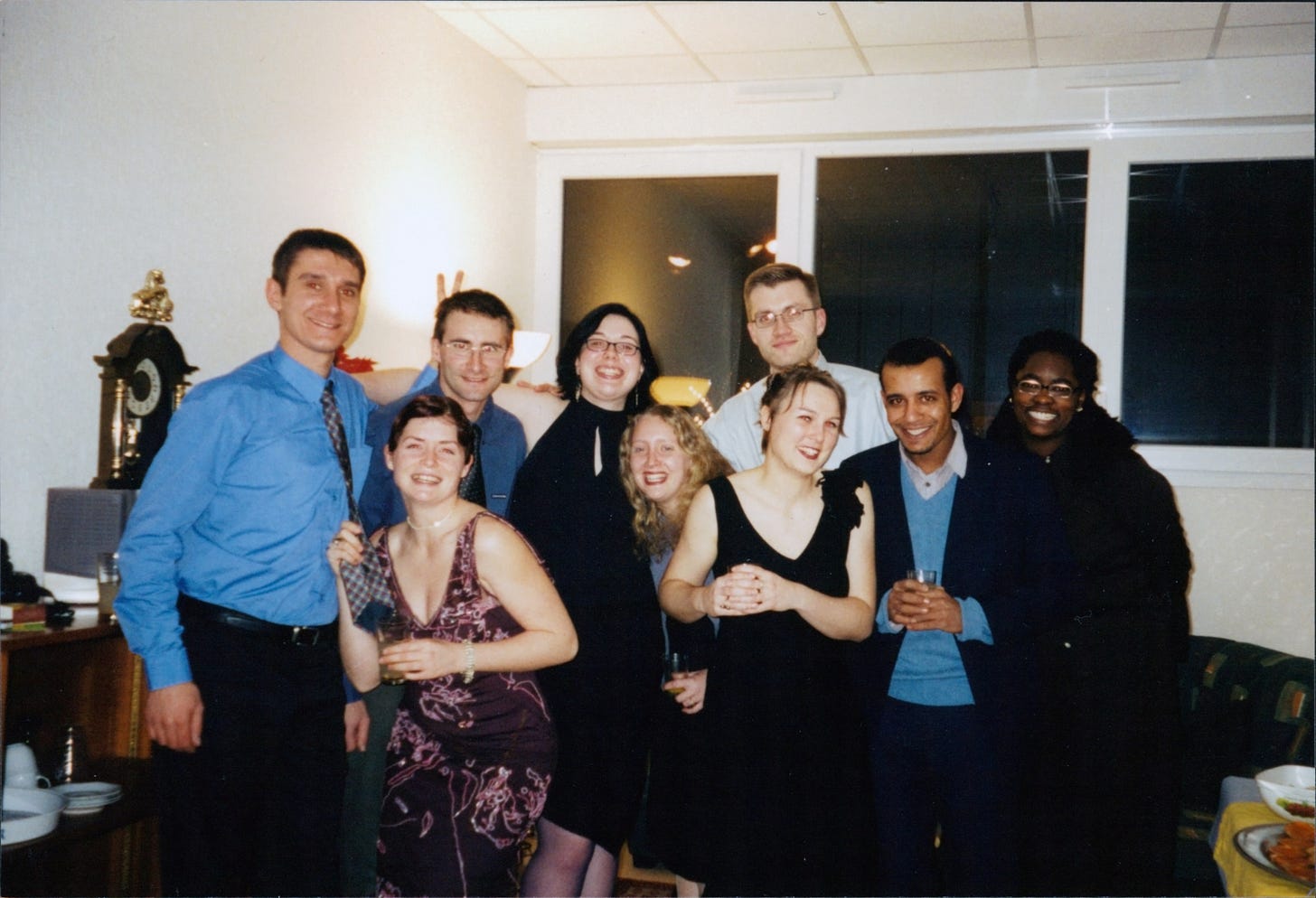 A group of men and women in festive dinner dress standing and smiling for the camera.