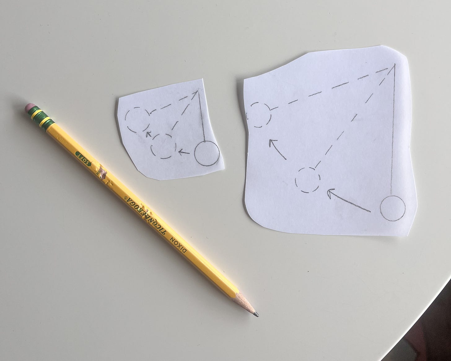 pencil next to two cut-out pictures of pendulums swinging in small and large pencil next to two cut-out pictures of pendulums swinging in small and large