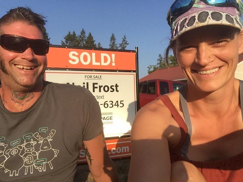 Me and my partner sitting in front of a house sold sign