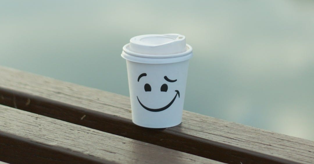 white and blue disposable cup on brown wooden table white and blue disposable cup on brown wooden table
