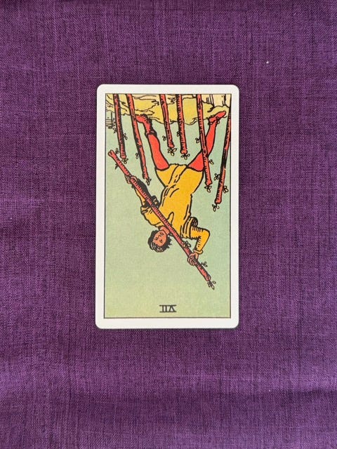 tarot card upside down shows a man among 6 wands, holding up a 7th in fighting posture.