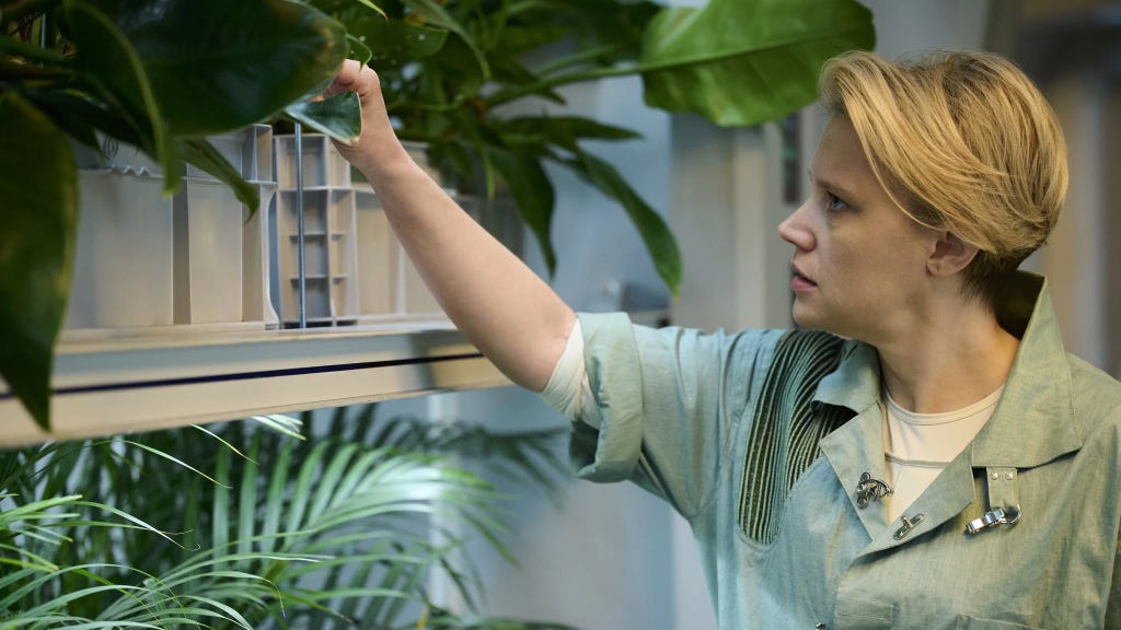 In the Blink of an Eye | Still features Kate McKinnon as a scientist observing plants. In the Blink of an Eye | Still features Kate McKinnon as a scientist observing plants.