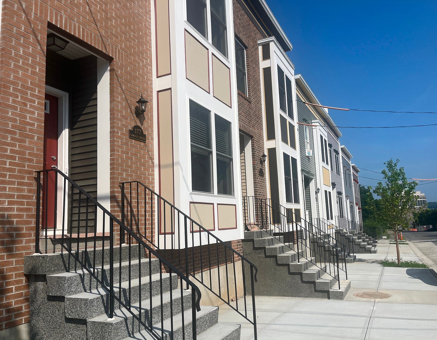 Row of new townhouses with brick exteriors and colorful doors.