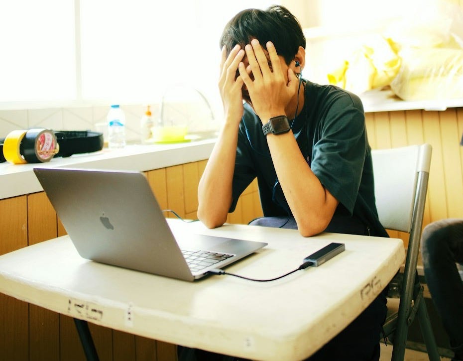 a person sitting at a desk with a laptop and a cell phone