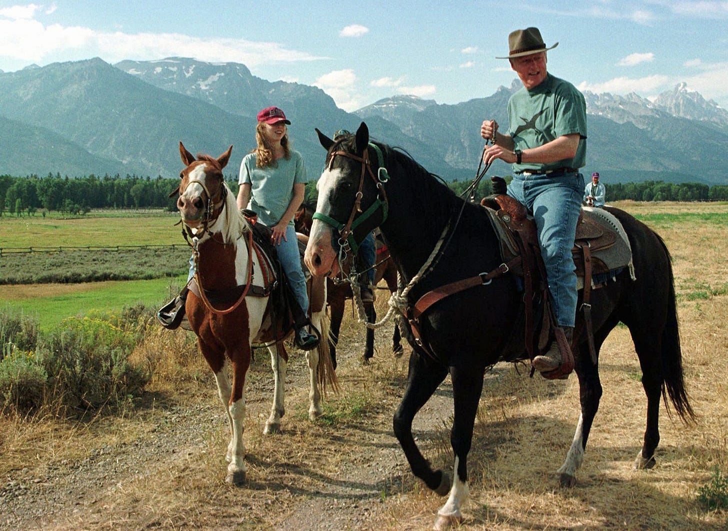 President Bill Clinton and daughter Chelsea enjoy horseback riding on a ranch near Jackson, Wyoming, with the Teton Mountains in the background, August 14, 1996. President Bill Clinton and daughter Chelsea enjoy horseback riding on a ranch near Jackson, Wyoming, with the Teton Mountains in the background, August 14, 1996.