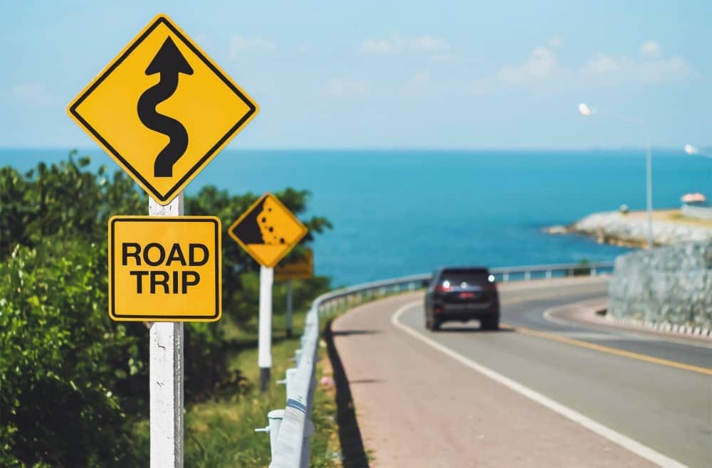 Winding beach road with yellow sign that reads Road Trip