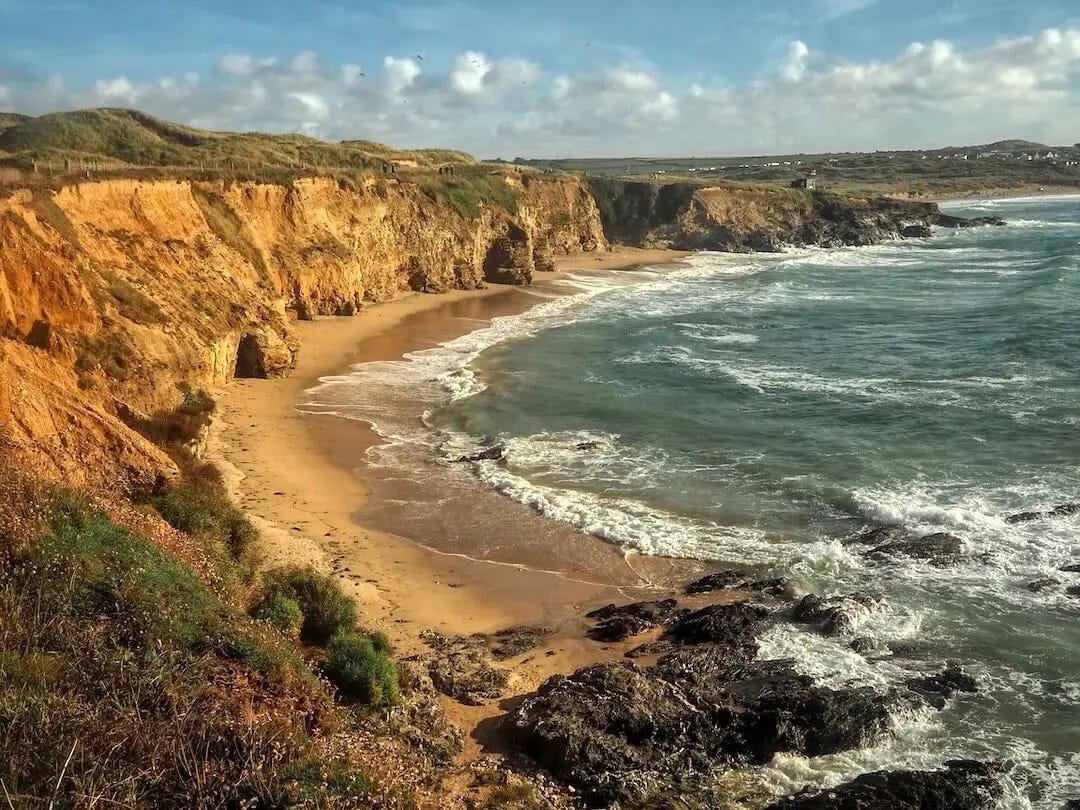 A sandy beach with sandstone cliffs
