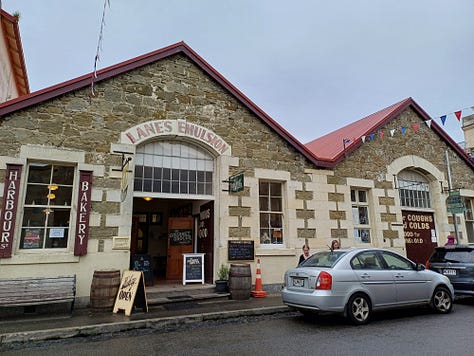 A series of stone buildings, created in a variety of styles, from fairly plain and study to huge and ornate. All of the buildings are made from or incorporate creamy limestone, some soot-blackened or weathered. On the right top is a locomotive engine cab with a large screw mounted at the front, located to indicate that it has just burst up out of the ground. The bottom right features a whitestone bridge fording a stream, over which the main street is laid.