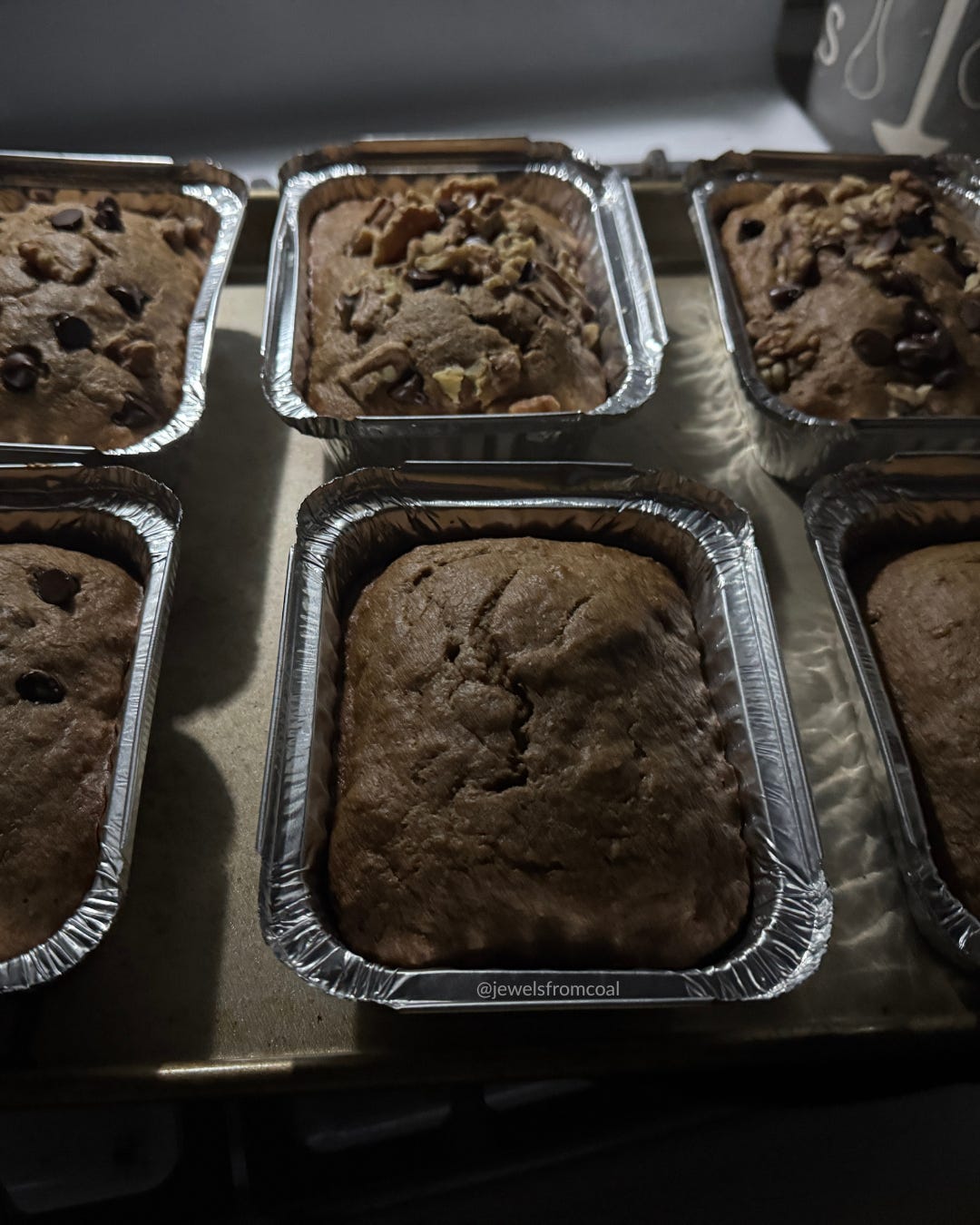 Freshly baked loaves cooling on the stove, their tops rich brown with chocolate chips and walnuts. Freshly baked loaves cooling on the stove, their tops rich brown with chocolate chips and walnuts.