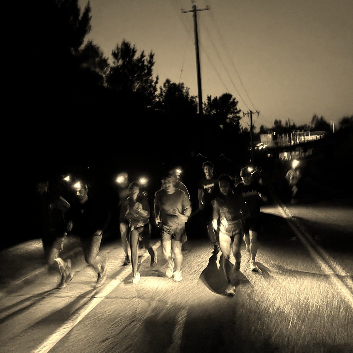 Group of runners wearing headlamps in the dark.