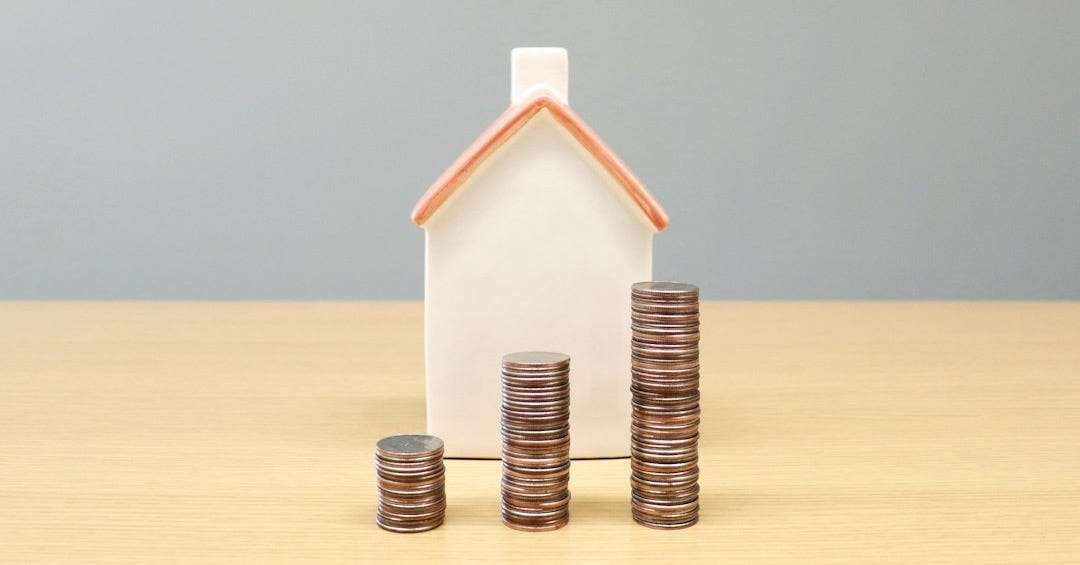 a house and stacks of coins on a table a house and stacks of coins on a table
