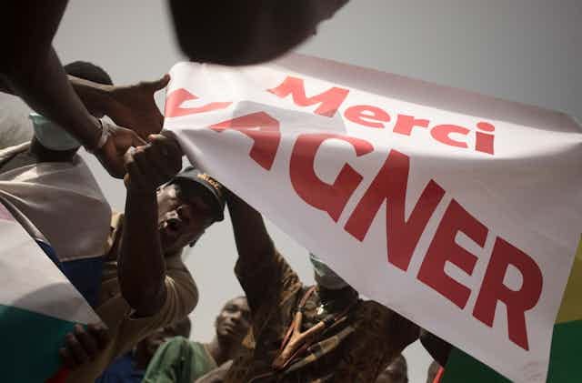 A group of people waving a white banner with red prints A group of people waving a white banner with red prints