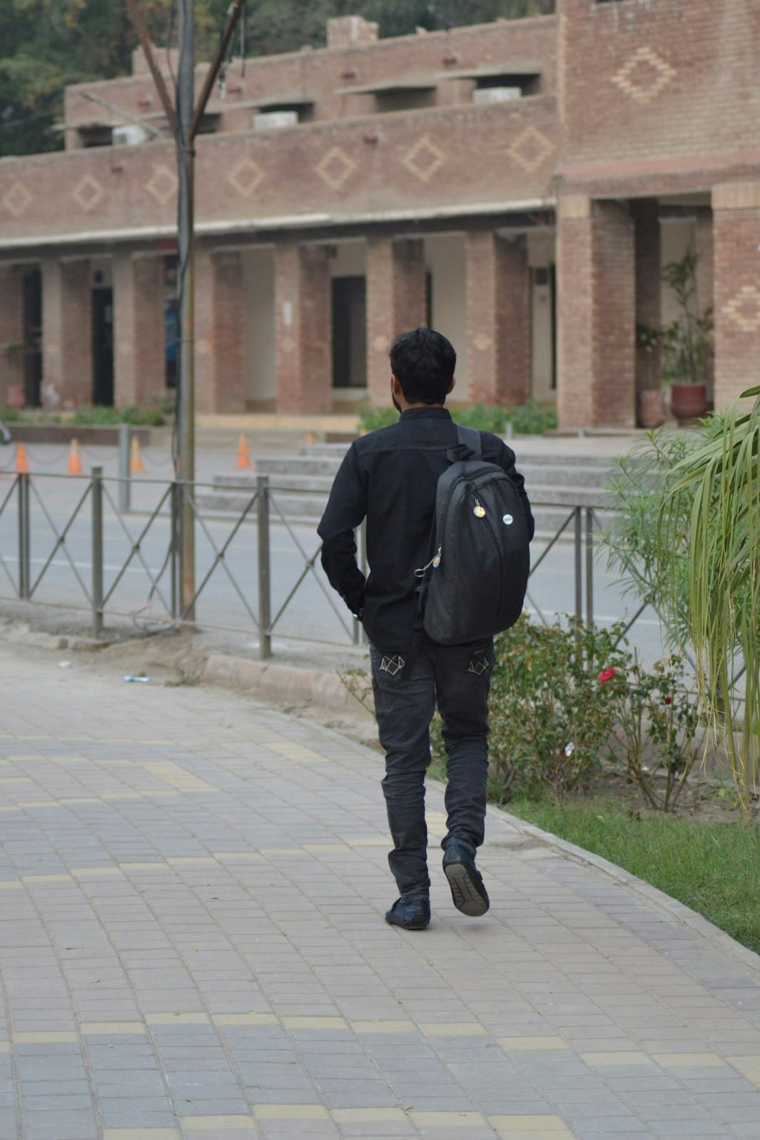 A man with a backpack walking down a sidewalk