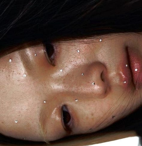 girl sitting on the bathroom floor brusing teeth and stretching like a ballerina in pyjama's, prada lip balm, girl with tiny gem stones all over her face