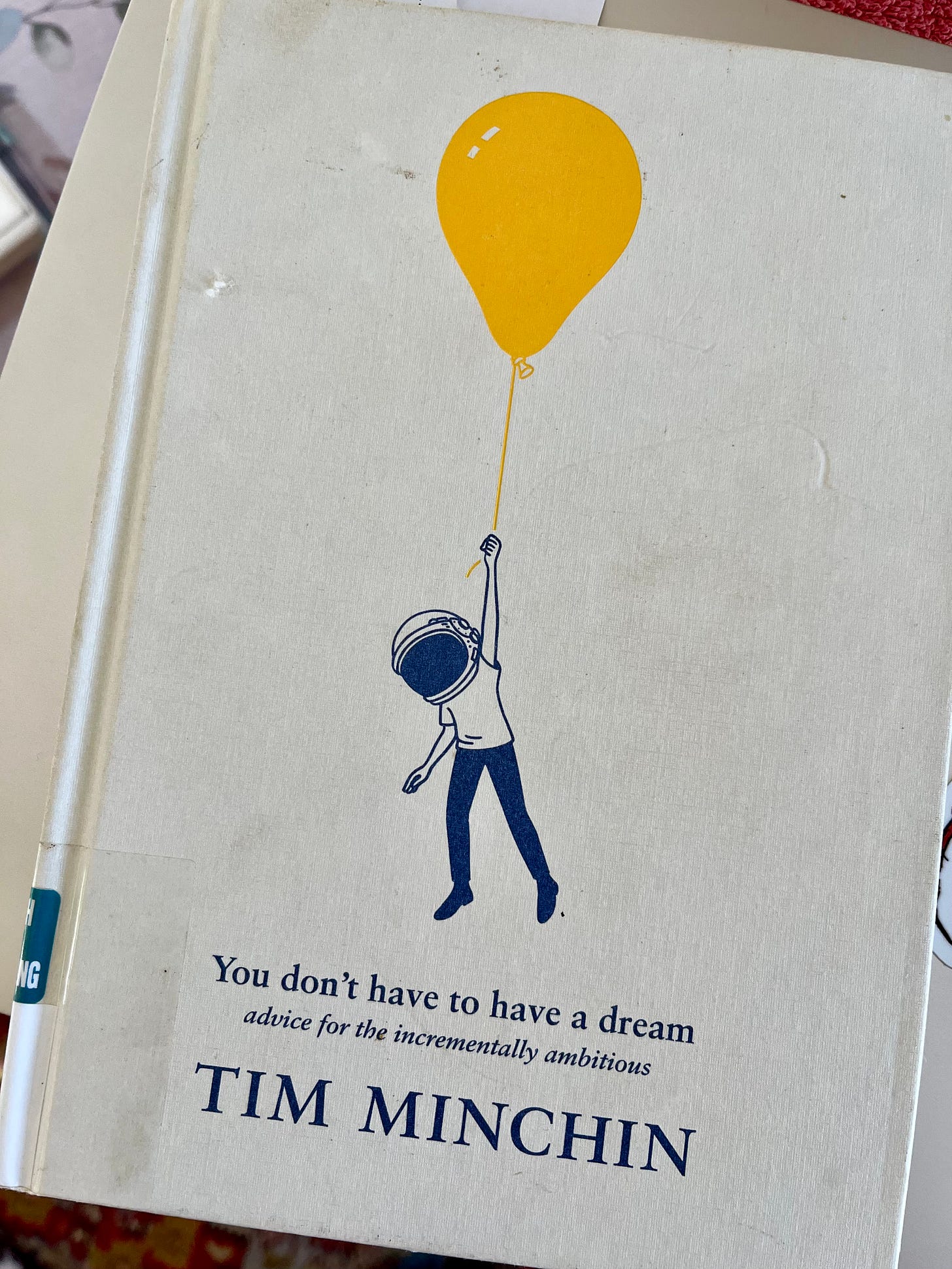 photo of the cover of You don’t have to have a dream by Tim Minchin. The cover has a figure wearing a space helmet holding on to the string of a big yellow balloon and they are floating