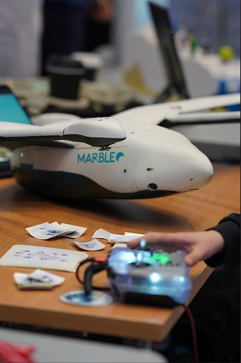 Three photos of people at a stand showcasing a drone. 