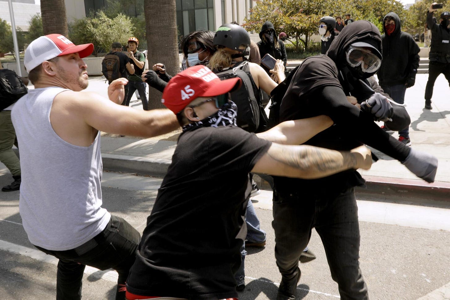 Two men fight a hooded person