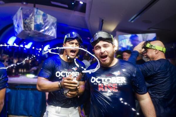 Toronto Blue Jays' Santiago Espinal, left, and Alejandro Kirk celebrate the team's wild-card playoff berth, after a win over the Boston Red Sox in a baseball game Friday, Sept. 30, 2022, in Toronto. (Christopher Katsarov/The Canadian Press via AP)