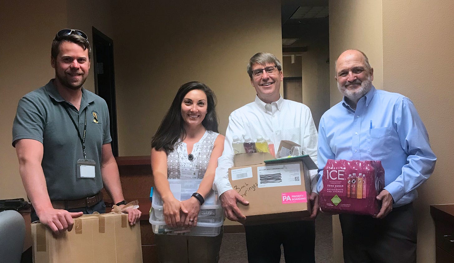 Three men and one woman pose smiling for a photo, their arms full of boxes or food. Three men and one woman pose smiling for a photo, their arms full of boxes or food.