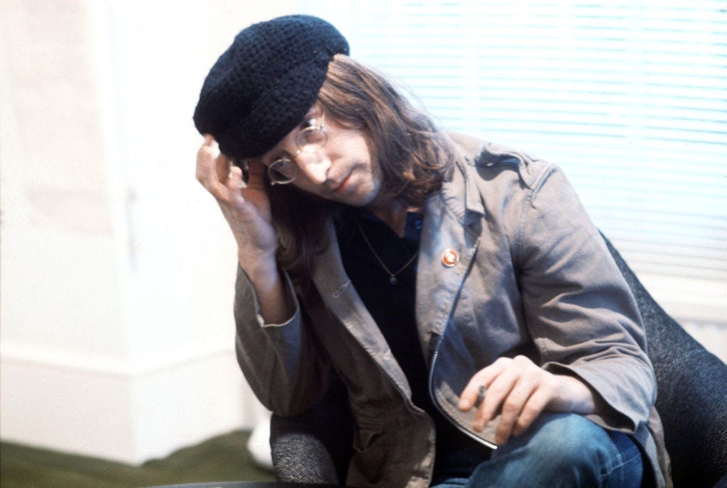 A man in a grey coat and knit cap with round glasses sits on a chair A man in a grey coat and knit cap with round glasses sits on a chair