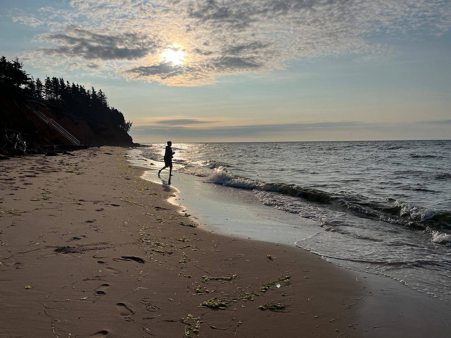 A silouetted figure of a teenager in the distance on a beach
