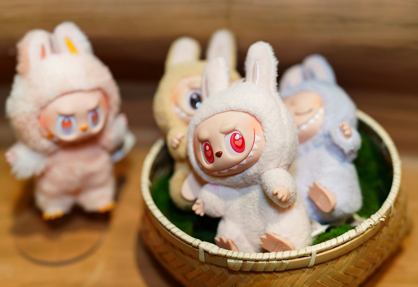 A basket of fuzzy rabbit-costumed Labubu collectible figures with toothy grins and big red eyes. A basket of fuzzy rabbit-costumed Labubu collectible figures with toothy grins and big red eyes.