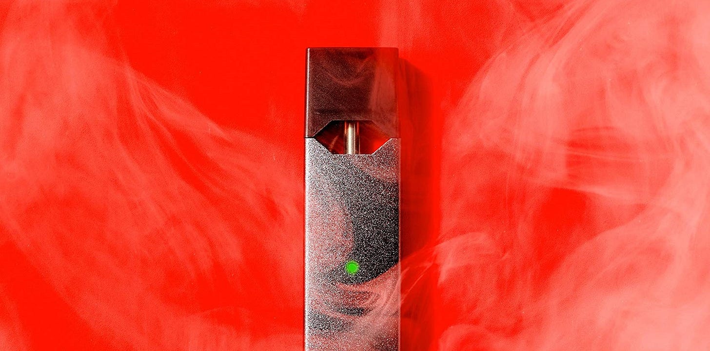 A Juul vaporized over a red background, surrounded by smoke