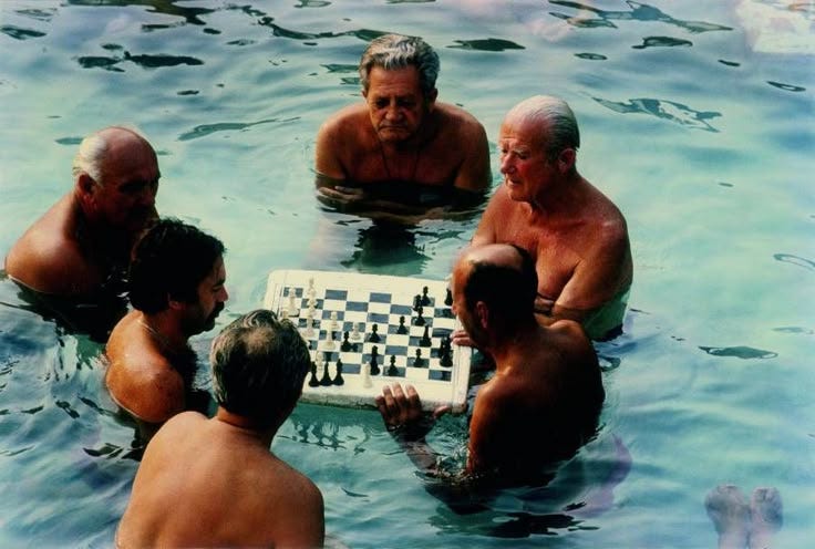 This may contain: four men playing chess in the water with their backs turned to look like they are swimming