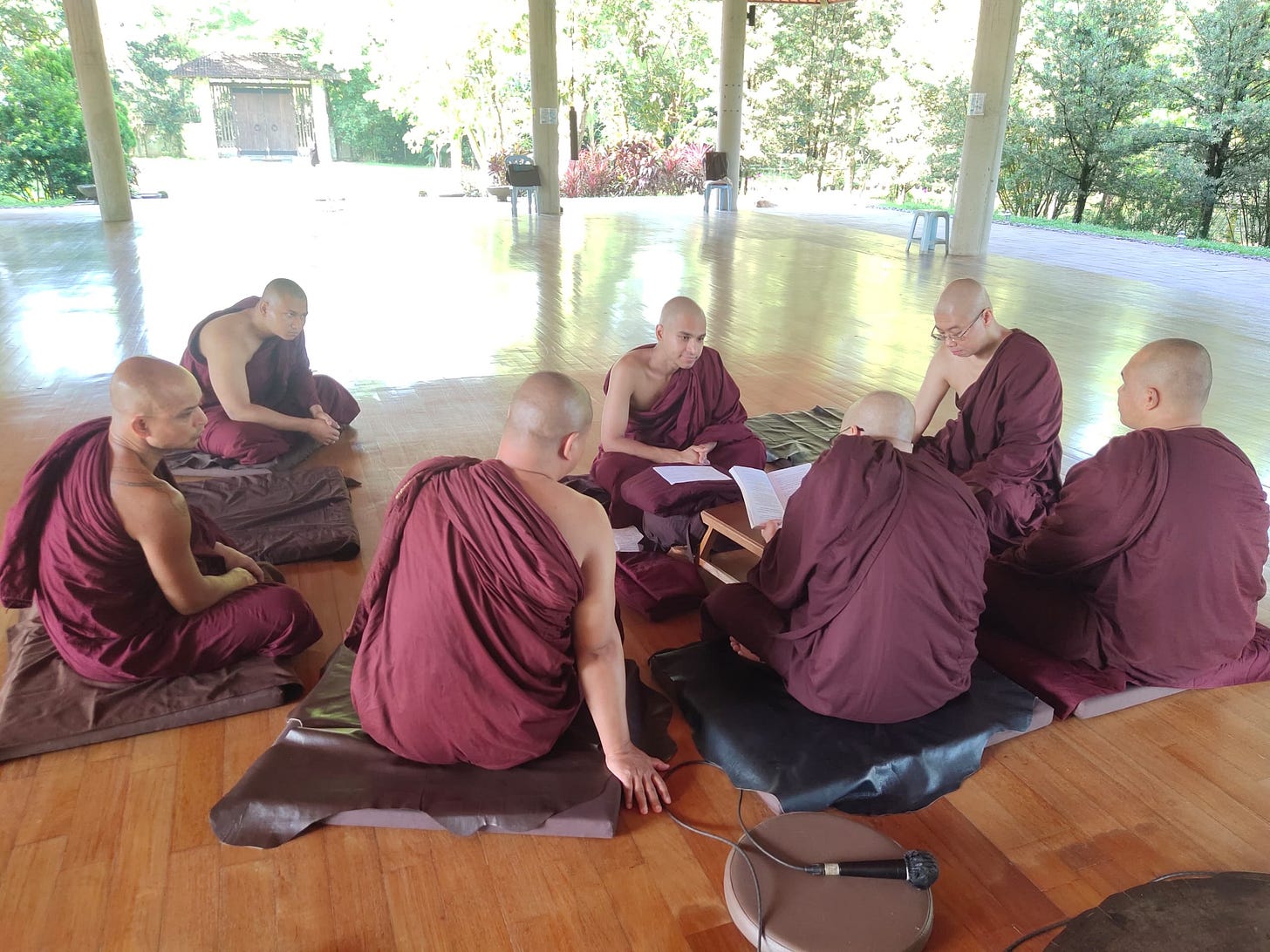 group of monks sitting together in red robes, ordination ceremony