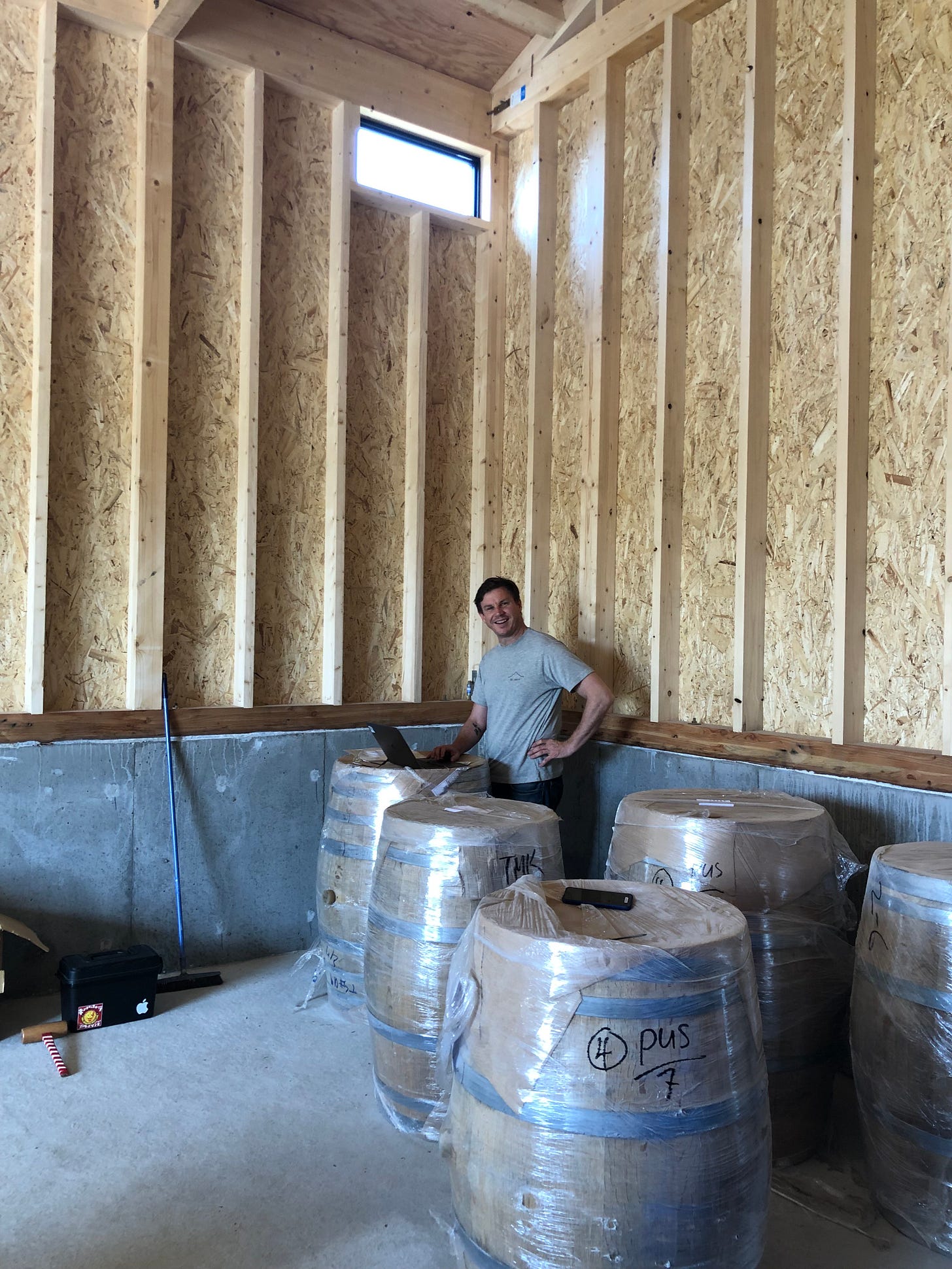 Founder conducting online meeting with laptop balanced on whisky barrel in sparse warehouse
