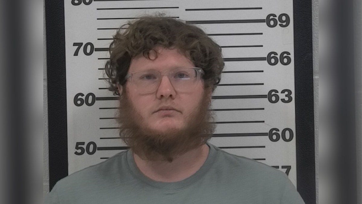 Man with facial hair posing in a mugshot