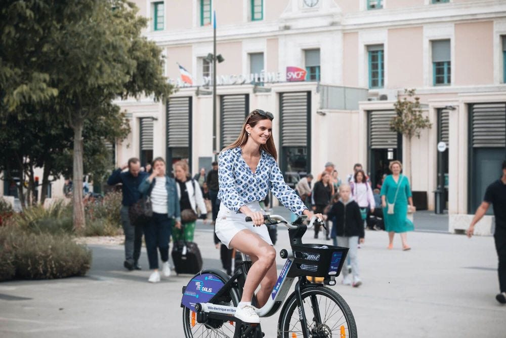 Jeune femme a velo devant une gare