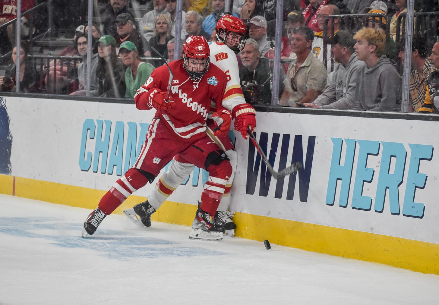 Quinn Finley checks Denver Pioneers player while looking down at puck. 