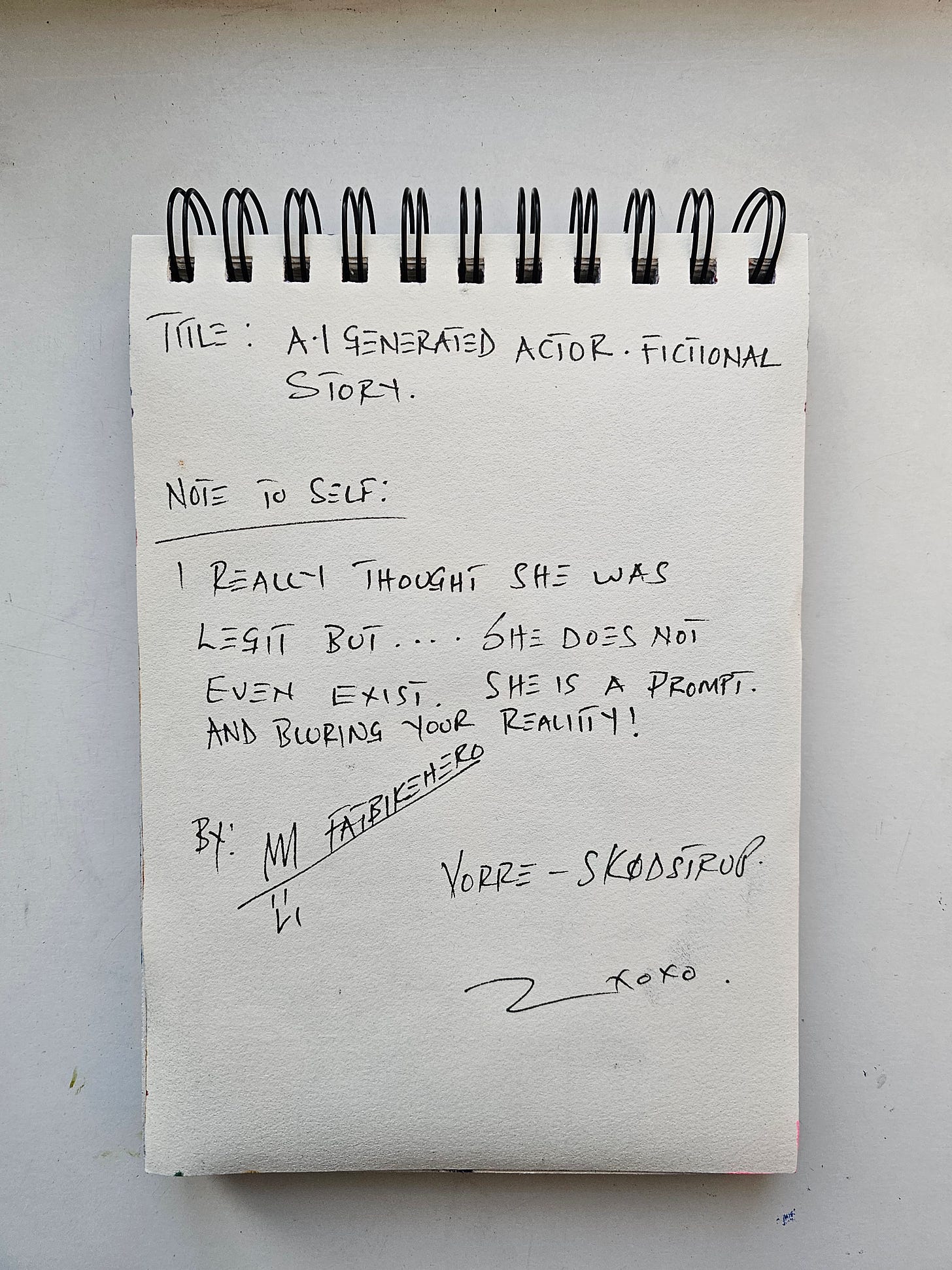 Alt Text: A vertical photo of a spiral-bound sketchbook page. Handwritten black ink text reads: "TITLE: A.I GENERATED ACTOR - FICTIONAL STORY. NOTE TO SELF: I REALLY THOUGHT SHE WAS LEGIT BUT... SHE DOES NOT EVEN EXIST. SHE IS A PROMPT. AND BLURING YOUR REALITY!" Signed "By: Fatbikehero" with a doodle of a face and the location "Vorre - Skødstrup."