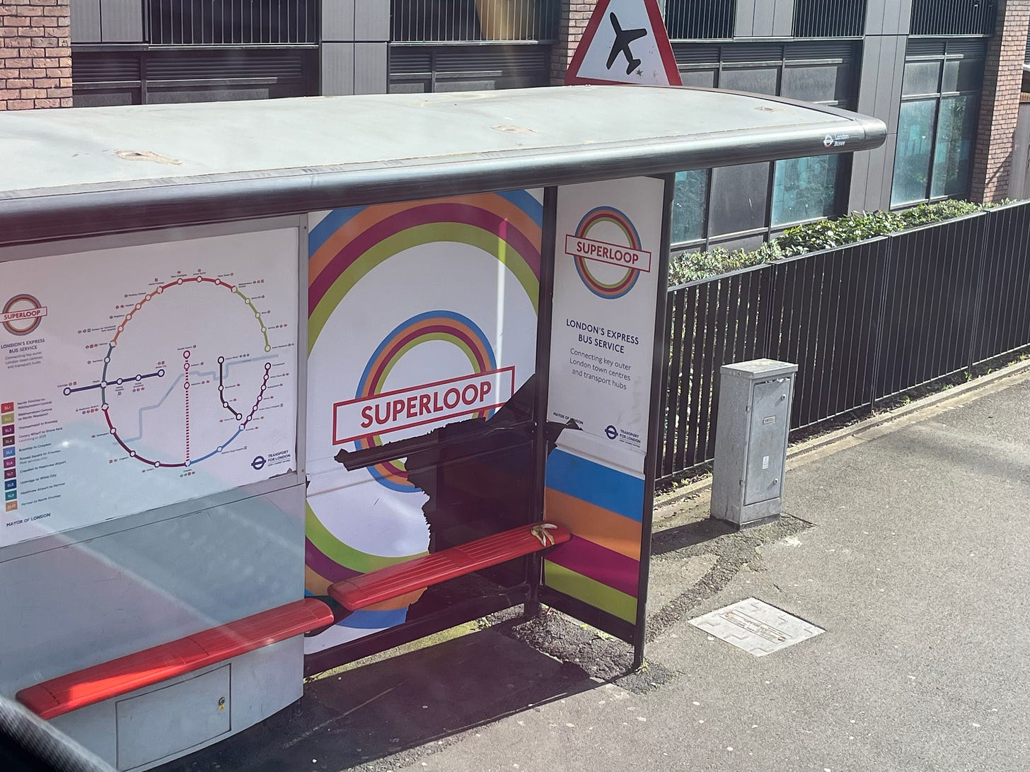 Photo of a bus shelter in Superloop branding that's been damaged.