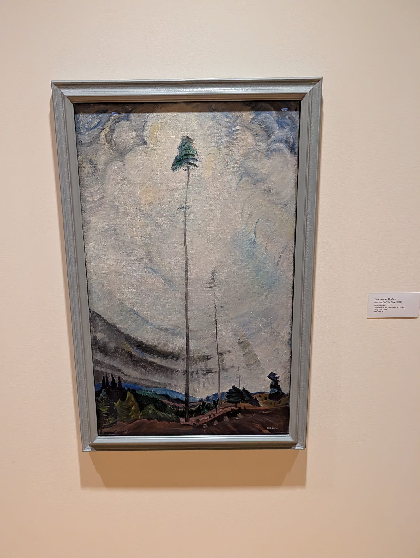 Emily Carr's "Scorned as Timber, Beloved of the Sky" hanging on a gallery wall. It depicts a tall, skinny, mostly-bare pine mast with light radiating around it from the sun breaking through clouds behind it. Emily Carr's "Scorned as Timber, Beloved of the Sky" hanging on a gallery wall. It depicts a tall, skinny, mostly-bare pine mast with light radiating around it from the sun breaking through clouds behind it.
