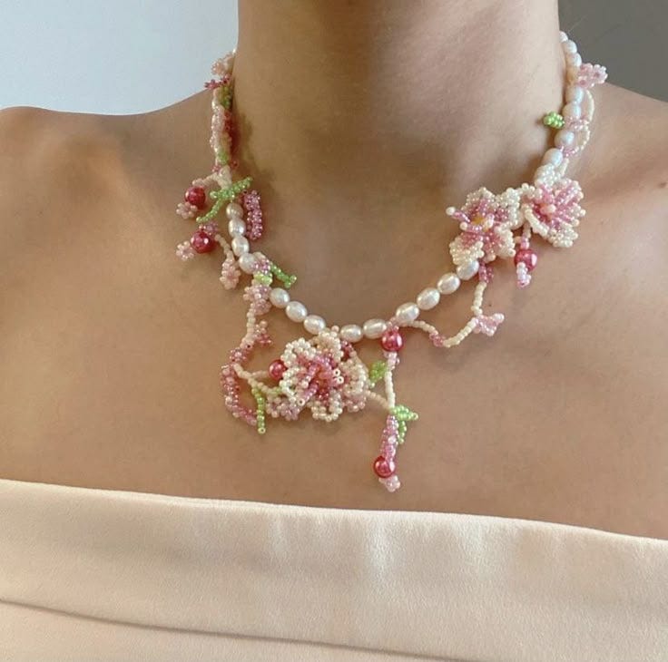 This may contain: a woman wearing a pink and green beaded necklace with flowers on the side,