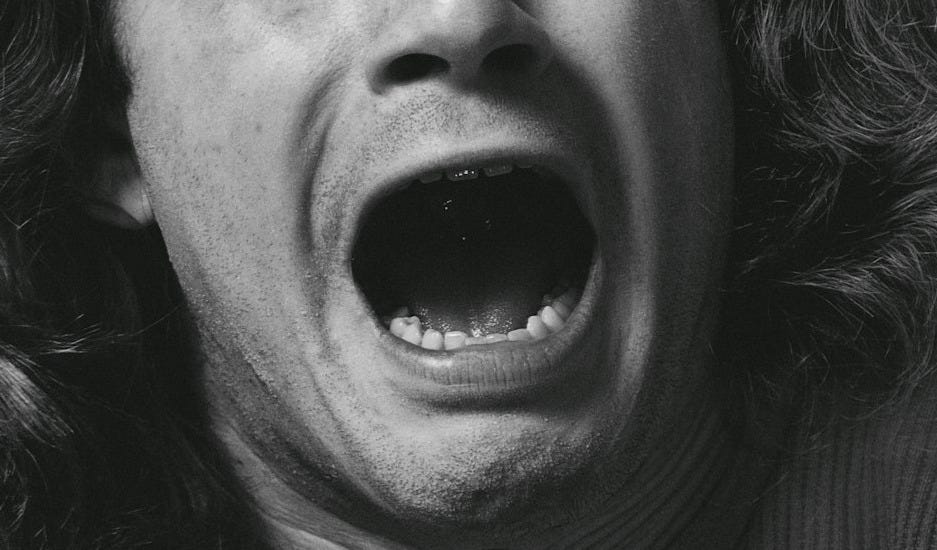 grayscale photography of man with mouth open
