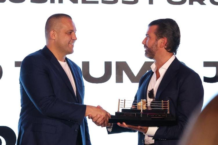 Umar Kremlev shakes hands with Donald Trump Jr., who is holding a model of a boxing ring. Umar Kremlev shakes hands with Donald Trump Jr., who is holding a model of a boxing ring.